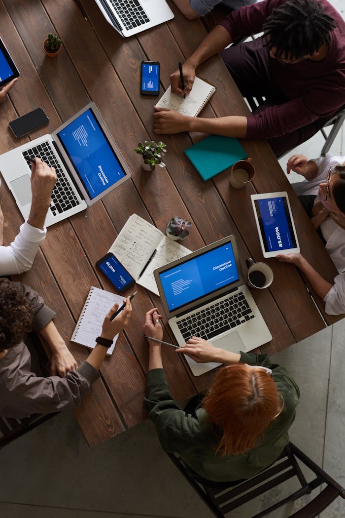 digital A diverse group of professionals brainstorming with laptops and notepads in a modern office.